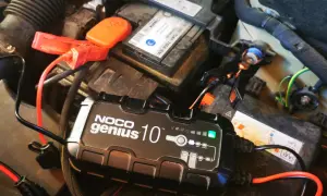 Ładowarka NOCO Genius 10 podłączona do akumulatora samochodowego, rozpoczyna proces odsiarczania akumulatora.