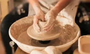 Mani esperte modellano l'argilla su un tornio, creando un pezzo unico di artigianato locale.