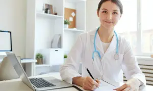 Lekarka w białym kitlu z niebieskim stetoskopem notuje dane, analizując przyrost beta hcg.