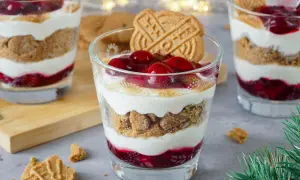 Festliche Desserts im Glas mit Kirschen, Kekskrümeln und Sahne, garniert mit Spekulatius.