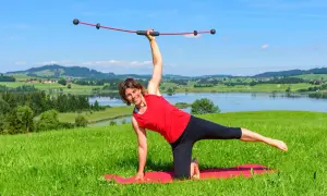Frau macht Yoga mit einem Schwingstab, dem Testsieger für Balance-Training, vor malerischer Alpenkulisse.