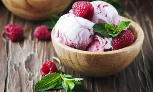 Pyszny sorbet malinowy w drewnianej miseczce, ozdobiony świeżymi malinami i miętą. Idealny deser, jak zrobić sorbet malinowy.