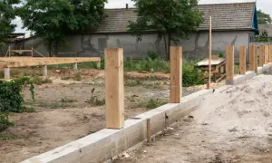 Budowa ogrodzenia: betonowy fundament i drewniane słupki czekają na dalsze prace. Jaki fundament pod ogrodzenie jest najlepszy?