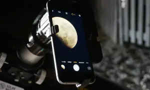Telefon z aparatem uchwycił zdjęcie księżyca w pełni, widocznego przez teleskop.