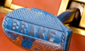 Stary, niebieski uchwyt hamulca z napisem "BRAKE". Rdza i odpryski farby sugerują, jaki smar do prowadnic hamulcowych byłby potrzebny.