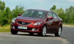 Czerwona Mazda 6 2.0 benzyna jedzie po drodze, za kierownicą siedzi mężczyzna.