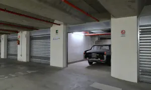 Un'auto d'epoca nera in un garage sotterraneo. Le porte a serranda chiuse e l'illuminazione suggeriscono che affittare garage conviene per proteggere il tuo veicolo.