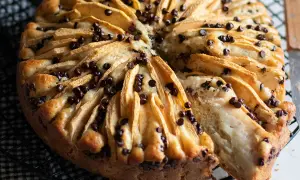 Una deliziosa torta di mele e cioccolato, con fette di mela disposte a raggiera e gocce di cioccolato fondente.