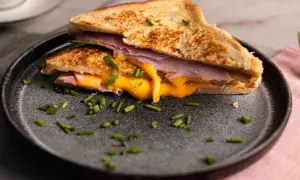 Herzhaftes French Toast mit Schinken und geschmolzenem Käse, garniert mit Schnittlauch.