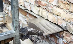 Wprowadzanie izolacji poziomej w starym domu. Widać fragment maszyny i wbijaną płytę izolacyjną w ceglaną ścianę.