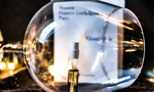 Mała próbka perfum Grand Soir Maison Francis Kurkdjian w szklanej kuli, otoczona ciepłym światłem.