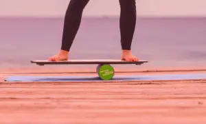 Füße balancieren auf einem Wackelbrett über einer Rolle.