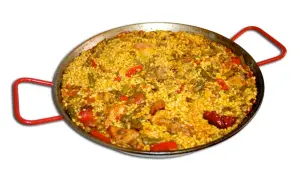 En stor paella med ris, kyckling, gröna bönor och paprika i en traditionell paellapanna med röda handtag.