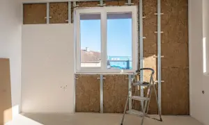 Installazione di sistemi di isolamento termico con lana di roccia e cartongesso, con una scala appoggiata al muro.
