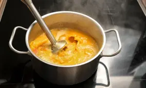 Blendowanie warzyw do zupy kremu, idealnej na dietę płynną. Gorąca para unosi się znad garnka.