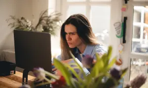 Zmarszczona kobieta przy laptopie, sfrustrowana z powodu braku połączenia z internetem.