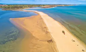 Piaszczyste plaże Chorwacji w całej okazałości. Długi, piaszczysty cypel otoczony turkusową wodą, z widokiem na miasteczko w oddali.
