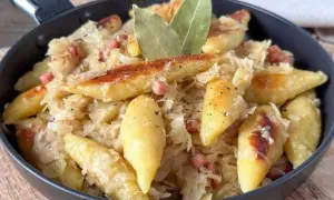 Nudeln mit Sauerkraut und Speck in einer Pfanne, garniert mit Lorbeerblättern.