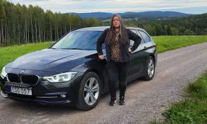 Kvinna vid en svart BMW kombi i svensk landsbygd. Kanske ett bmw b47 problem som gör att hon stannat här.