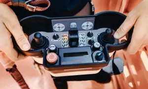 Operator próbuje sterować maszyną, ale brama nie reaguje na pilota. Widoczne przyciski i joysticki panelu sterowania.