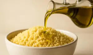 Olio d'oliva versato su couscous in una ciotola, mostrando la differenza tra cous cous e pasta.