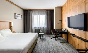 Nowoczesny pokój w jednym z **courtyard hotels Warsaw**. Duże łóżko, wygodne fotele i biurko przy oknie.