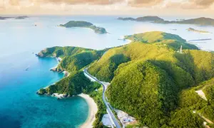 Malownicze Japonia plaże z turkusową wodą i zielonymi wzgórzami. Droga wije się wśród bujnej roślinności, prowadząc do ukrytych zatoczek.