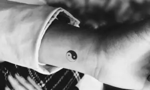 Mały tatuaż yin yang na nadgarstku. Symbolizuje równowagę i harmonię, a jego znaczenie jest głębokie.