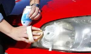 Manos limpiando un faro de coche con pasta blanca para pasar la ITV.
