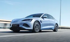 Un elegante veicolo elettrico BYD Seal sfreccia su un'autostrada soleggiata, con il cielo azzurro e le luci stradali sfocate sullo sfondo.