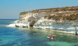 Malta, październik: kajaki w turkusowej wodzie przy klifie z jaskinią. Idealna pogoda na wodne przygody.