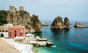 Scopri Castellammare del Golfo: case colorate, rovine antiche su scogliere rocciose e un mare cristallino con faraglioni.