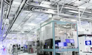 Czysty, nowoczesny zakład produkcyjny, gdzie powstają technologie dla największych firm IT na świecie. W tle widać linie produkcyjne i systemy transportowe.
