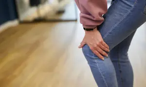 Frau hält schmerzhaft ihr Knie, was auf einen Meniskusriss hindeutet. Mögliche meniskusriss behandlung wird gesucht.
