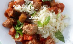 Herzhafte Salsiccia-Zubereitung in der Pfanne mit Auberginen, Paprika und Reis, garniert mit frischem Basilikum.