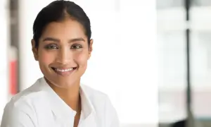 En kvinna ler, hennes blick och leende förmedlar en känsla av förtroende och positivitet, en form av indirekt kommunikation.