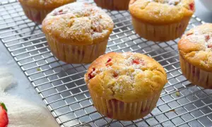 Frisch gebackene erdbeer muffins, mit Puderzucker bestäubt, auf einem Kuchengitter.