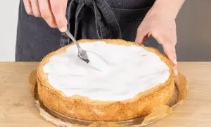 Landfrauen-Rezept: Ein goldbrauner Apfelkuchen wird mit einem Löffel mit süßem Guss überzogen.