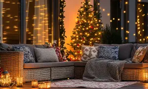 Un angolo accogliente per scoprire come addobbare fuori casa per Natale: divano, albero illuminato, lanterne e luci soffuse creano un'atmosfera magica.