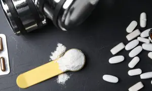 Bilancia, pillole e polvere bianca su un cucchiaio: cosa è meglio, proteine o aminoacidi per aumentare massa?