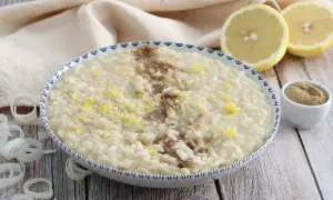 Un cremoso risotto alla liquirizia, guarnito con scorza di limone e una spolverata di polvere scura, pronto per essere gustato.