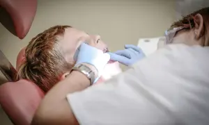 Chłopiec u dentysty, który bada jego usta. Może to być spowodowane bólem podniebienia przy zębach górnych.