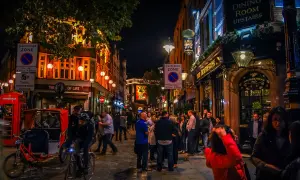En livlig gata i London på kvällen, med folk som minglar utanför pubar och restauranger, som påminner om stadens nattklubbar.