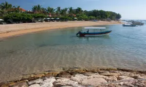 Spokojna plaża w Sanur z łodzią "Water Walk" kołyszącą się na turkusowej wodzie.