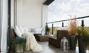 Przytulna loggia z rattanowymi meblami, miękkim kocem i ozdobnymi latarniami. Idealne miejsce na relaks.