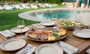 Una deliziosa grigliata di pesce con gamberi, tonno e orata, accompagnata da pane tostato, insalata e vino bianco, pronta per essere gustata a bordo piscina.