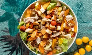 Insalata di pollo ricca con crostini dorati, pomodorini succosi, olive e patate dolci croccanti. Un piatto gustoso e colorato.