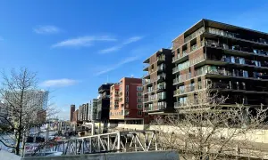 Moderne Gebäude mit Balkonen säumen das Wasser, wo Boote liegen. Die Magellan Terrassen bieten einen Blick auf die Hafencity.
