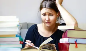Joven con libros apilados, pensativa, buscando qué hacer cuando te aburres.