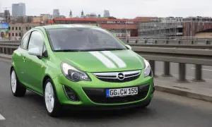 Zielony Opel Corsa D z białymi pasami na masce, z nowymi żarówkami w reflektorach, jedzie po moście.